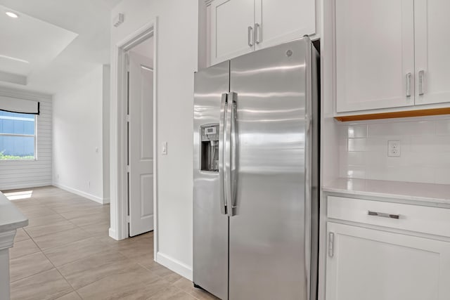 kitchen with white cabinets, light countertops, stainless steel refrigerator with ice dispenser, and backsplash