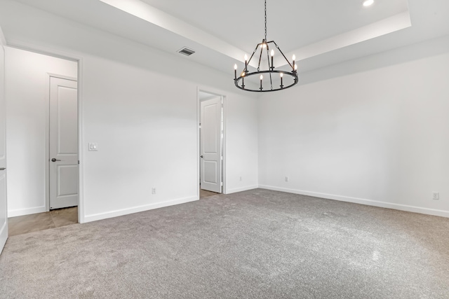 empty room featuring light colored carpet, a raised ceiling, visible vents, and baseboards