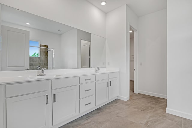 full bathroom featuring double vanity, a shower stall, baseboards, and a sink