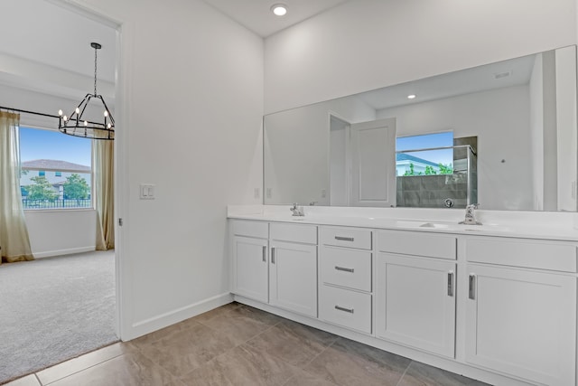 full bathroom with double vanity, a shower stall, baseboards, and a sink