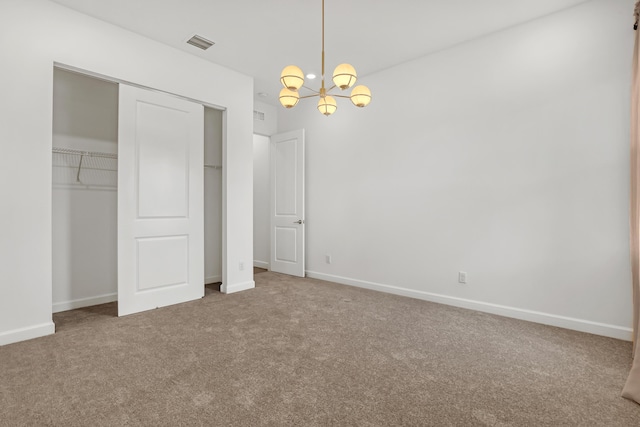 unfurnished bedroom featuring baseboards, visible vents, carpet flooring, a chandelier, and a closet