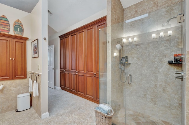 bathroom featuring lofted ceiling, toilet, visible vents, tile walls, and a shower stall