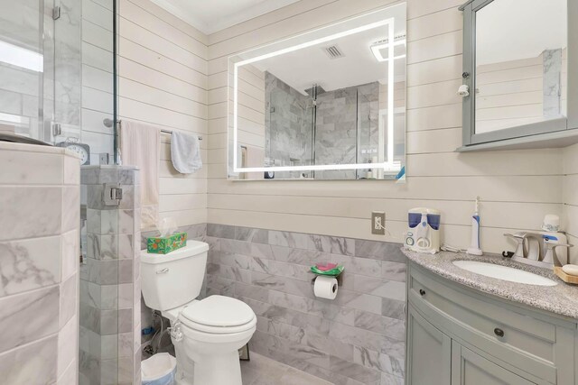 bathroom with toilet, a stall shower, vanity, and tile walls