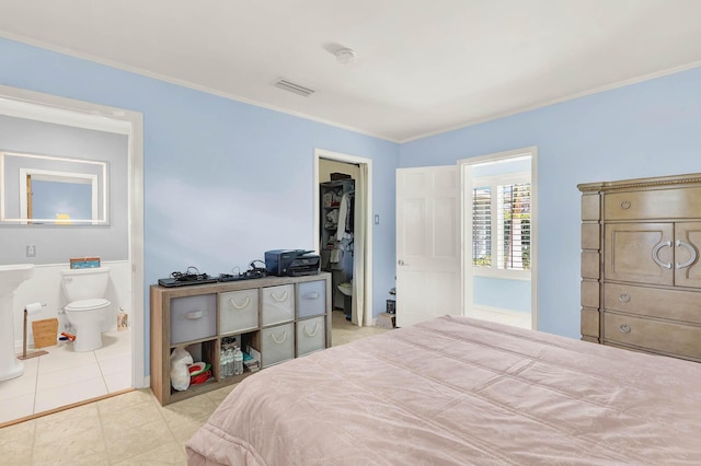 bedroom featuring light tile patterned floors, visible vents, ornamental molding, and ensuite bathroom