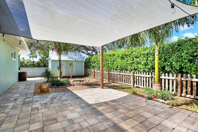 view of patio / terrace with a fenced backyard, a storage unit, and an outbuilding