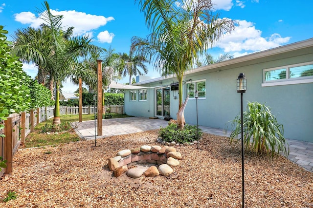 rear view of house featuring an outdoor fire pit, a fenced backyard, a patio, and stucco siding