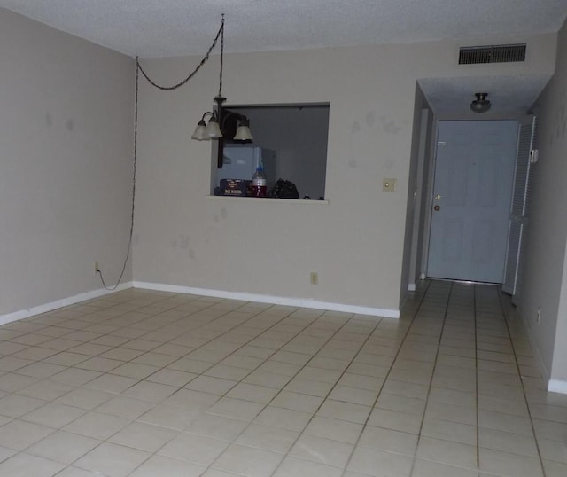 spare room featuring light tile patterned floors, visible vents, a textured ceiling, a chandelier, and baseboards