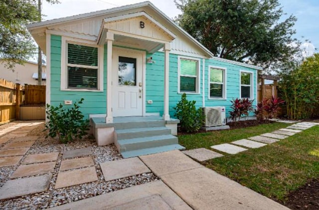 bungalow featuring board and batten siding, fence, and central AC unit