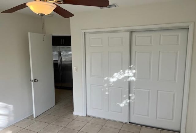 interior space with light tile patterned floors, a closet, visible vents, a ceiling fan, and freestanding refrigerator