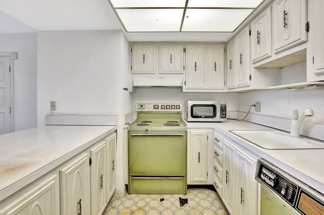 kitchen featuring appliances with stainless steel finishes, light floors, light countertops, under cabinet range hood, and a sink