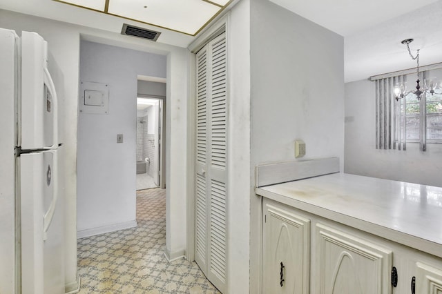 hallway featuring light floors, baseboards, visible vents, and a chandelier