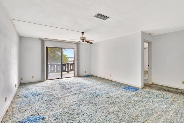 spare room with a textured ceiling, visible vents, baseboards, a ceiling fan, and carpet