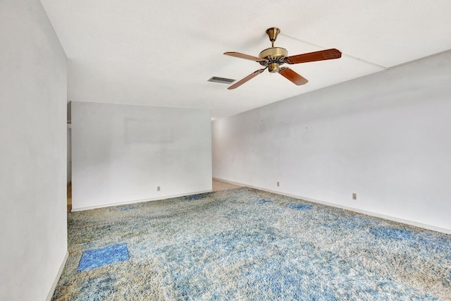 carpeted empty room with baseboards, visible vents, and a ceiling fan