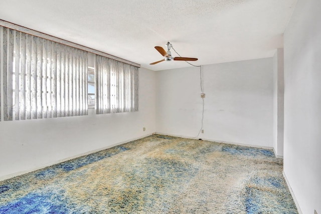 spare room featuring carpet, a textured ceiling, baseboards, and a ceiling fan