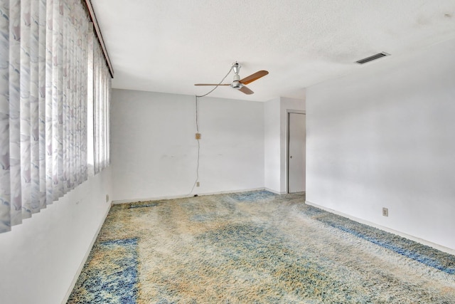 carpeted spare room featuring a textured ceiling, ceiling fan, visible vents, and baseboards