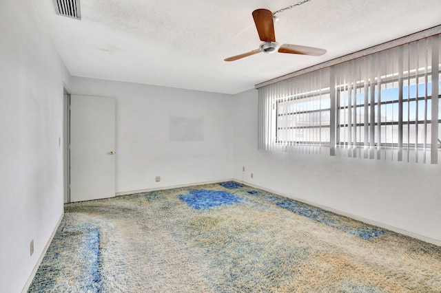 carpeted empty room featuring baseboards, ceiling fan, visible vents, and a textured ceiling