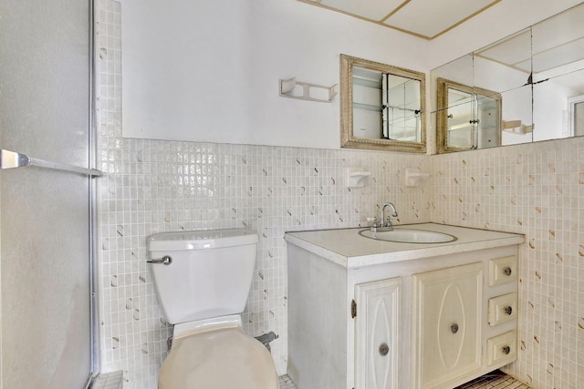 bathroom with toilet, vanity, and tile walls