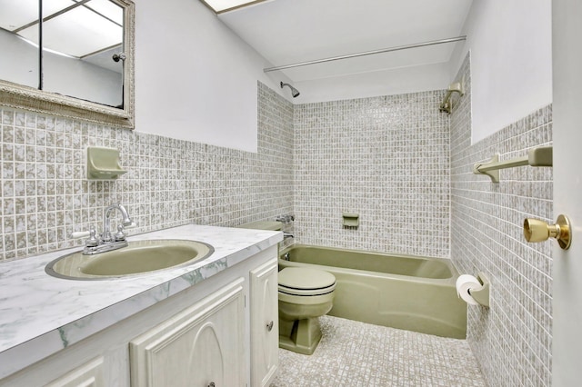 full bath with toilet, tile patterned floors,  shower combination, vanity, and tile walls