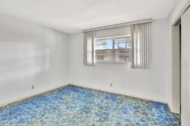 spare room with carpet, a textured ceiling, and baseboards