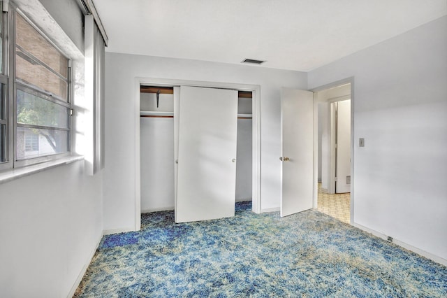 unfurnished bedroom with carpet floors, visible vents, and a closet