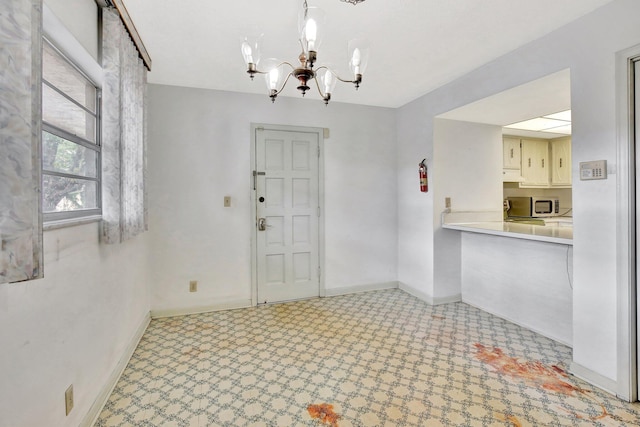 foyer entrance with a chandelier, baseboards, and tile patterned floors