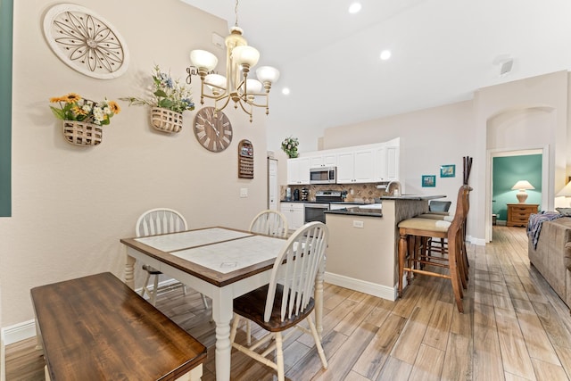 dining space with recessed lighting, baseboards, light wood finished floors, and an inviting chandelier