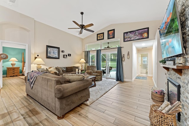 living room featuring light wood-style flooring, a fireplace, a ceiling fan, baseboards, and vaulted ceiling