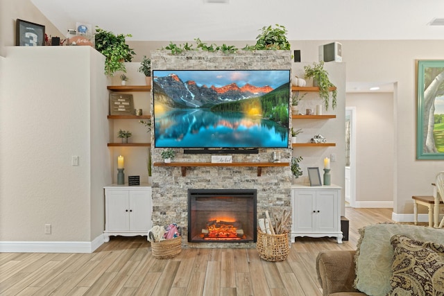 living area featuring light wood-type flooring, a fireplace, and baseboards