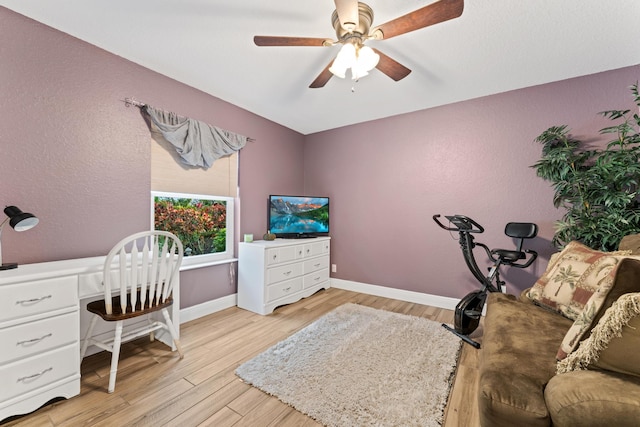 office area featuring light wood-type flooring, built in study area, a ceiling fan, and baseboards