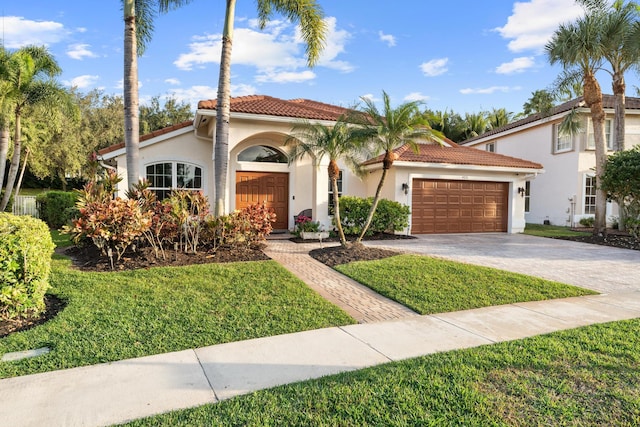 mediterranean / spanish-style house featuring a garage, a front lawn, decorative driveway, and a tiled roof