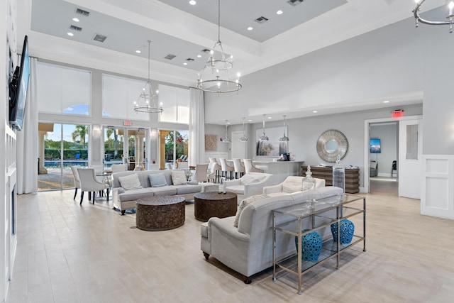 living area with crown molding, light wood-style floors, visible vents, and a notable chandelier