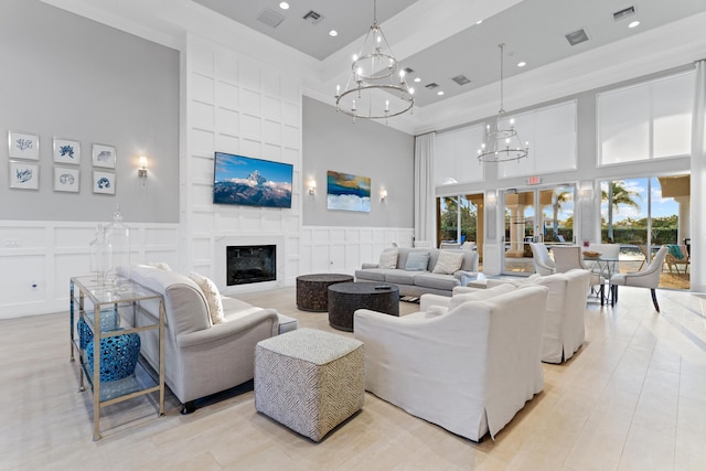 living room featuring visible vents, a decorative wall, a high ceiling, an inviting chandelier, and a large fireplace