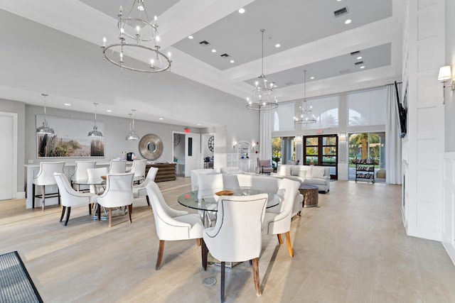 dining room with a chandelier, light wood-type flooring, visible vents, and a high ceiling