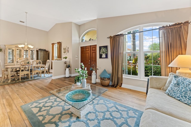 living room with a chandelier, high vaulted ceiling, wood finished floors, and baseboards