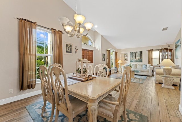 dining space featuring high vaulted ceiling, visible vents, a chandelier, light wood-type flooring, and baseboards