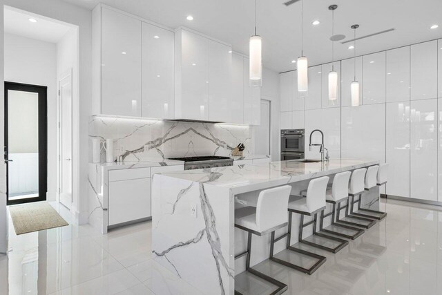 kitchen featuring light stone countertops, decorative light fixtures, a kitchen breakfast bar, and white cabinetry