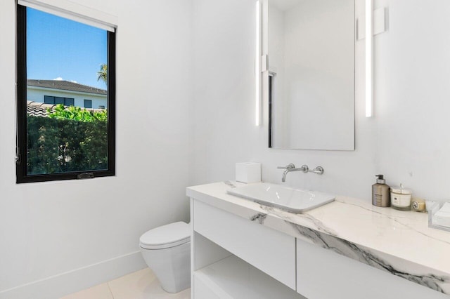 half bath with baseboards, vanity, toilet, and tile patterned floors