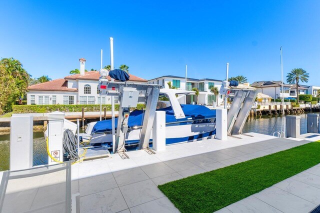 view of swimming pool featuring boat lift, a residential view, a water view, a dock, and a pool with connected hot tub