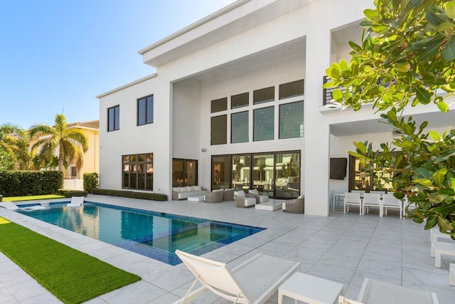 rear view of house with a patio, outdoor lounge area, a pool with connected hot tub, and stucco siding