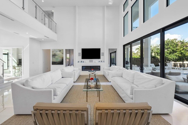 living area with a high ceiling, light tile patterned flooring, and a glass covered fireplace