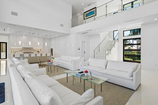 living room featuring recessed lighting, visible vents, stairway, and a towering ceiling