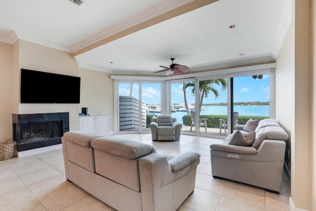 living area with a fireplace, a water view, ornamental molding, a ceiling fan, and light tile patterned flooring