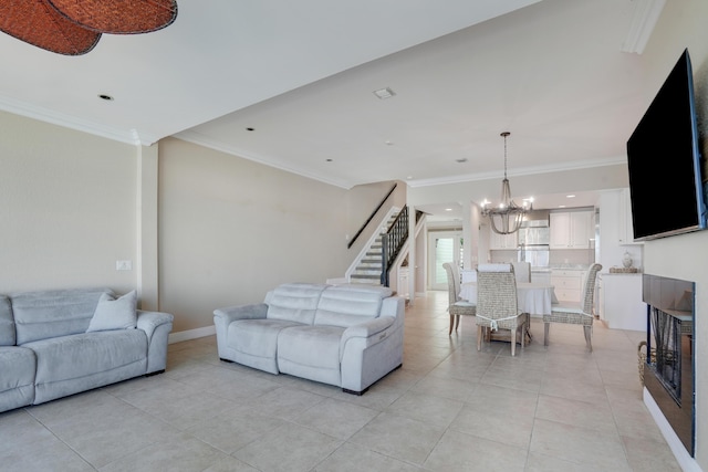 living area with ornamental molding, stairs, a fireplace, a notable chandelier, and light tile patterned flooring