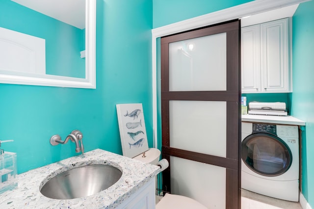 half bathroom with toilet, washer / clothes dryer, and vanity