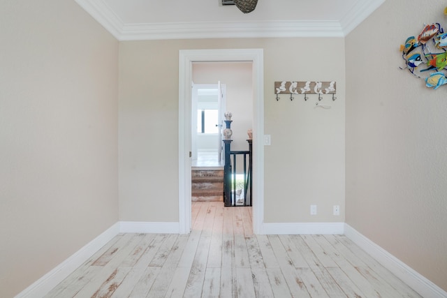 spare room featuring baseboards, light wood-style floors, and crown molding