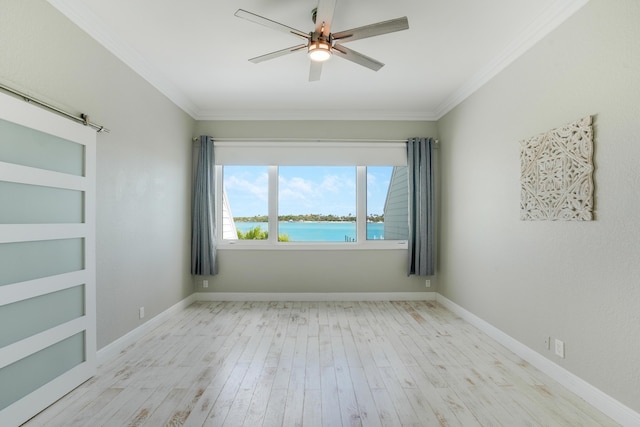 empty room with ceiling fan, a barn door, light wood-type flooring, and crown molding