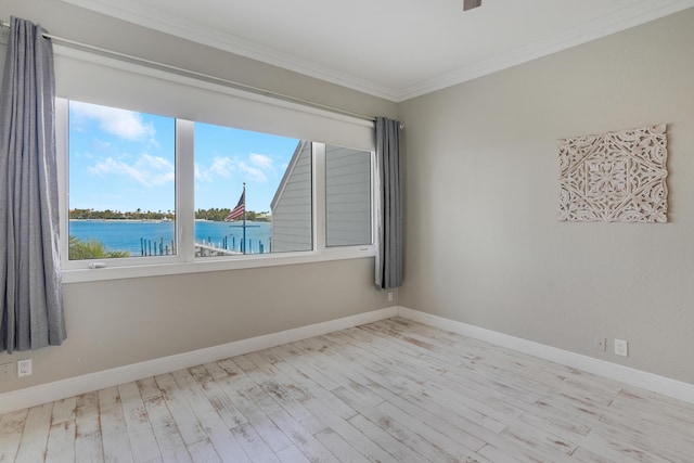 unfurnished room with baseboards, a water view, wood finished floors, and crown molding