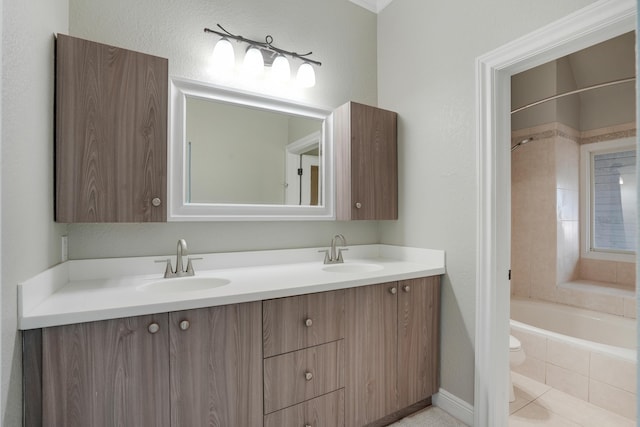 bathroom featuring a sink, tiled shower / bath, toilet, and double vanity