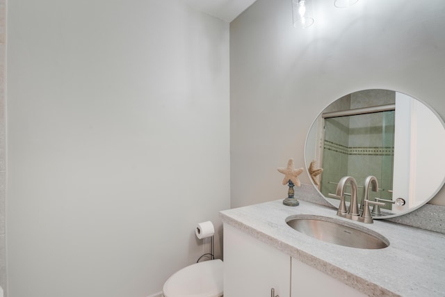 bathroom with a shower with shower door, vanity, and toilet