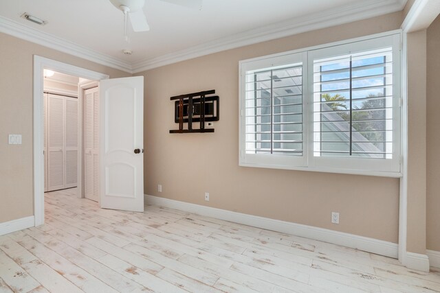 spare room featuring crown molding, visible vents, a ceiling fan, wood finished floors, and baseboards